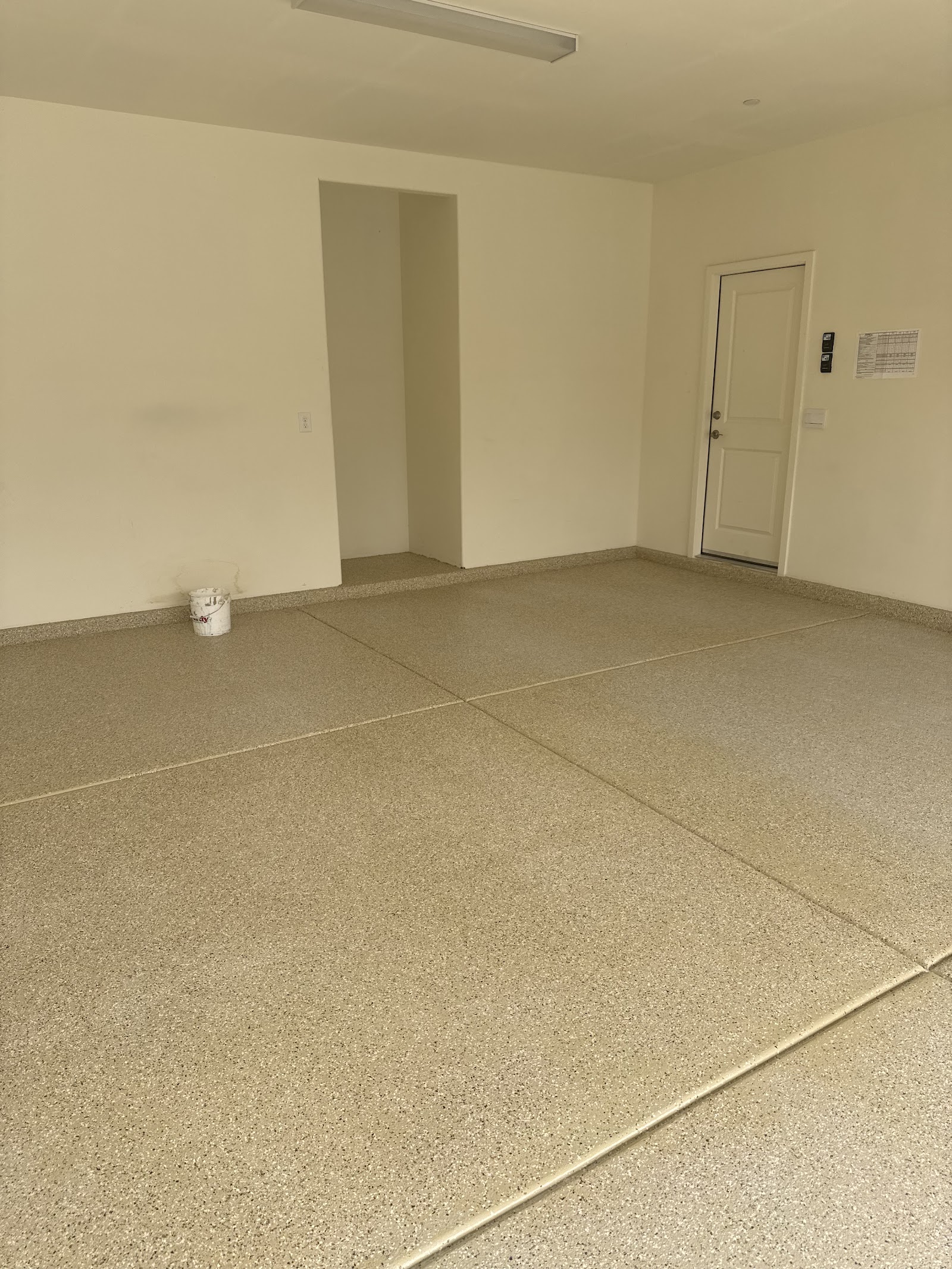 Empty garage with a newly applied speckled epoxy floor coating and interior door