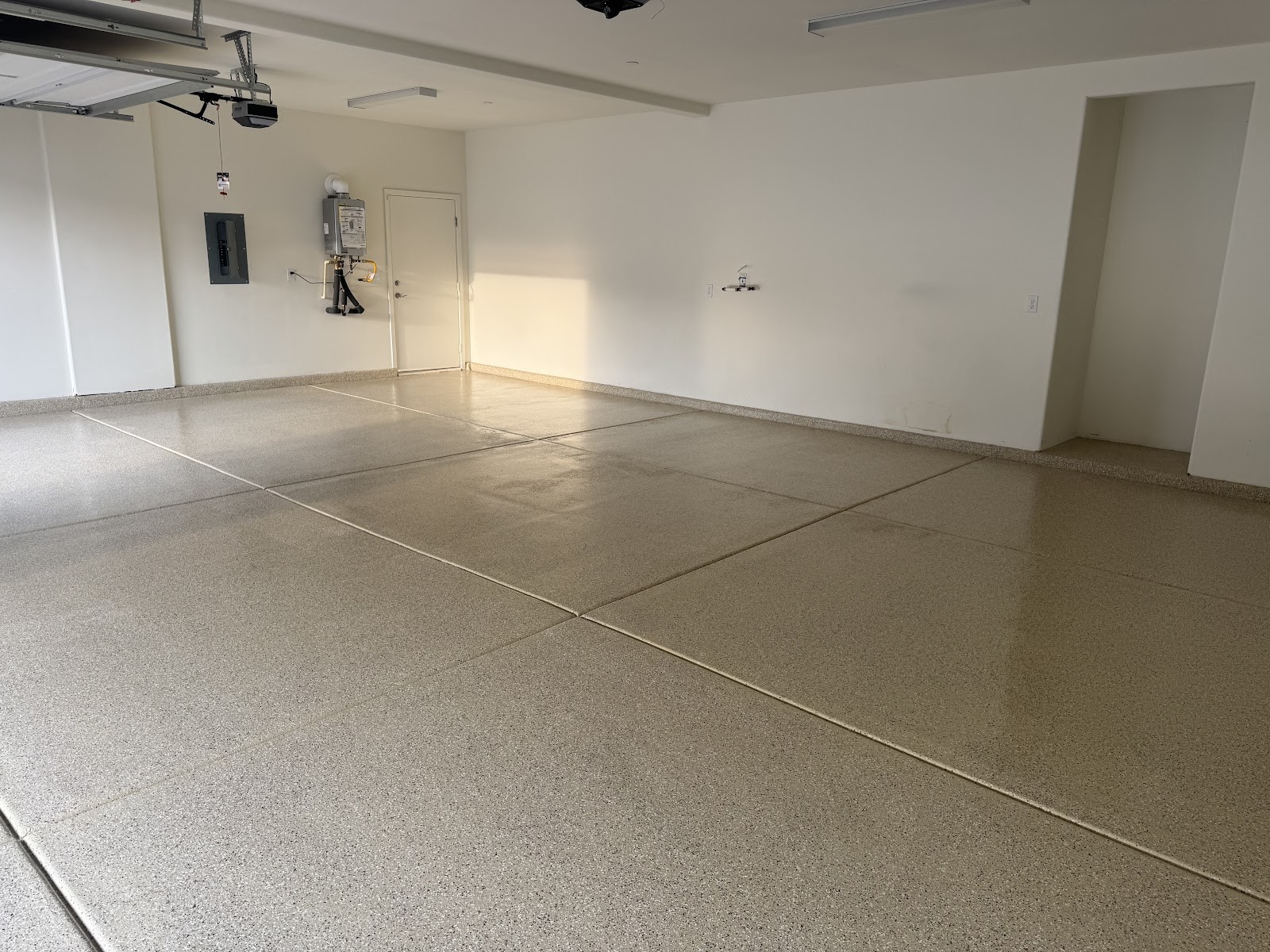 Finished speckled epoxy garage floor in a bright, clean garage with water heater and interior door